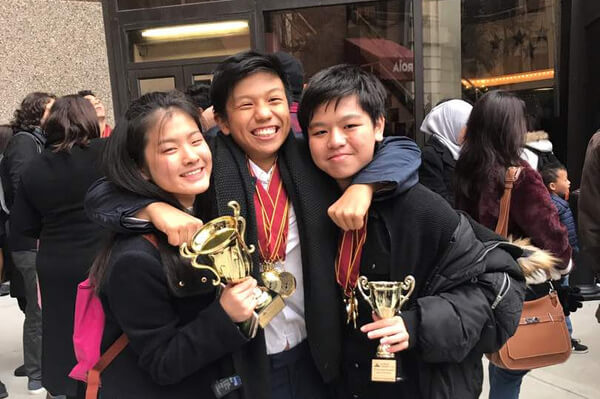 MIDP students celebrating their debate competition victory with trophies and medals